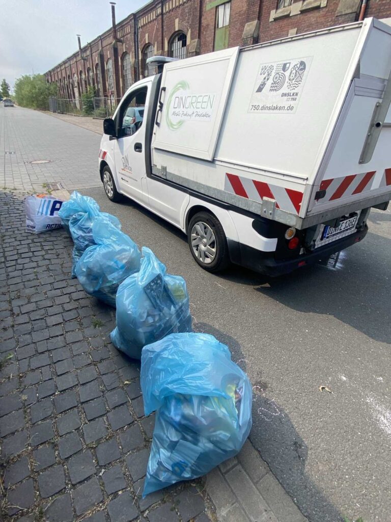 Müllsäcke stehen vor einem Auto des Din-Services